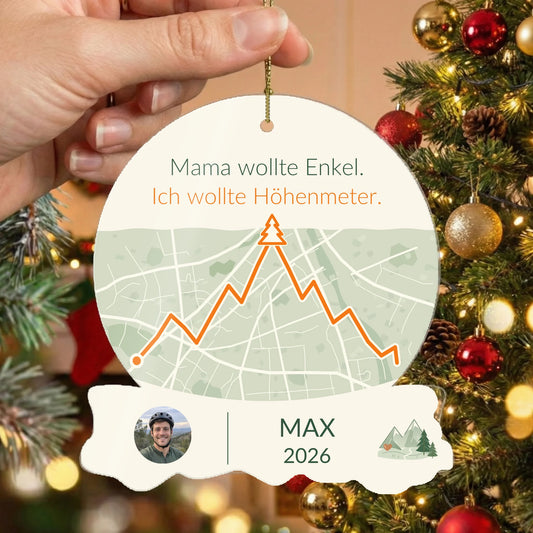 Christbaumschmuck „Mama wollte Enkel. Ich wollte Höhenmeter.“ vor dem geschmückten Weihnachtsbaum