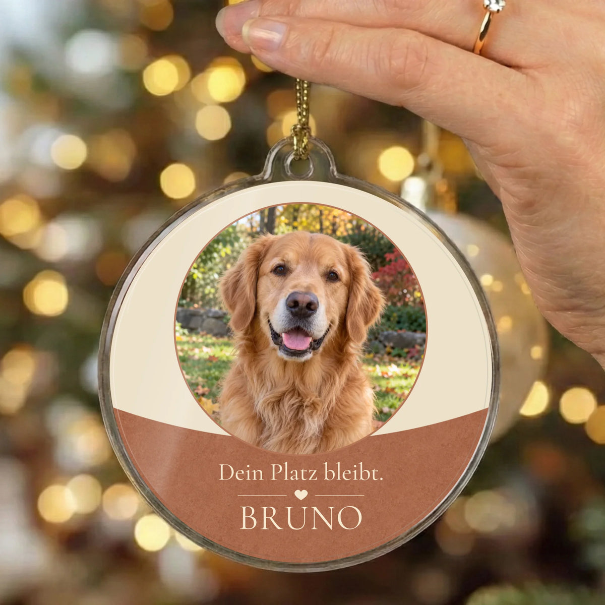 Christbaumschmuck „Dein Platz bleibt.“ in Creme und Terrakotta vor Weihnachtslichtern