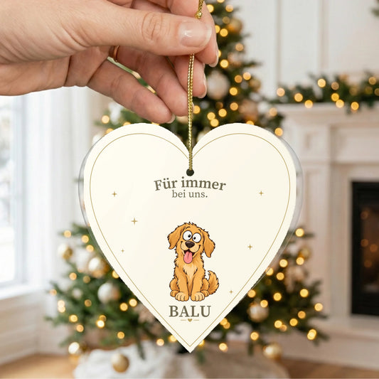 Herzförmiger Christbaumschmuck mit Hund und Namen vor dem Weihnachtsbaum