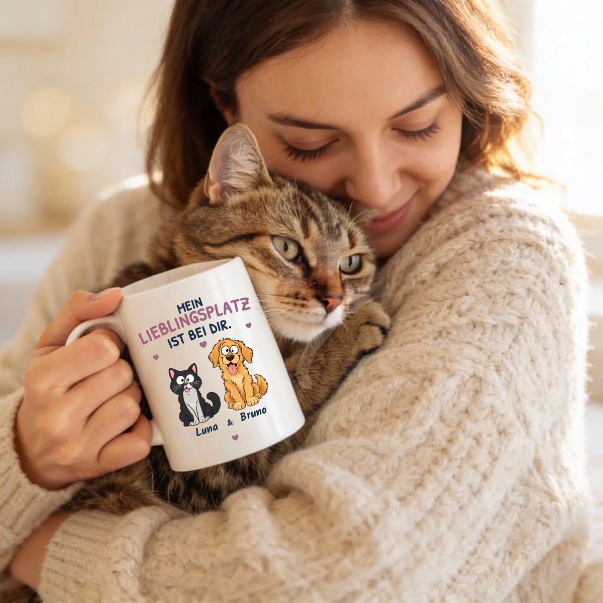Tasse „Mein Lieblingsplatz ist bei dir“ in der Hand einer Frau mit Katze