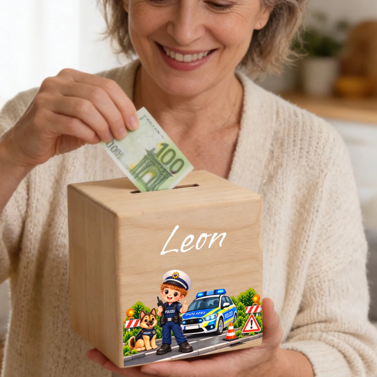 Holzspardose beim Einstecken eines Geldscheins mit Polizeimotiv und Name Leon
